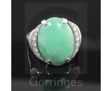 A platinum, cabochon jade and diamond set oval dress ring, the central stone bordered with graduated brilliants, size J/K.