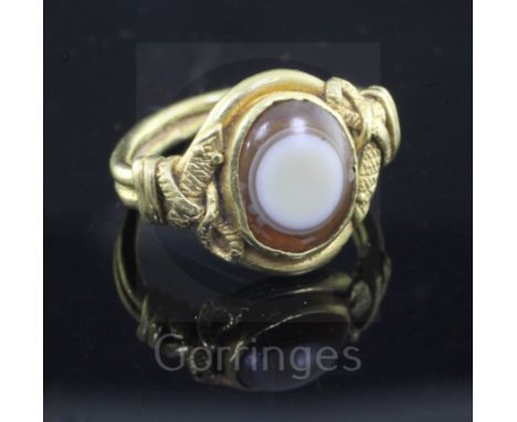 A Roman? gold and banded agate set oval ring, with pierced twin serpent shoulders, size H.