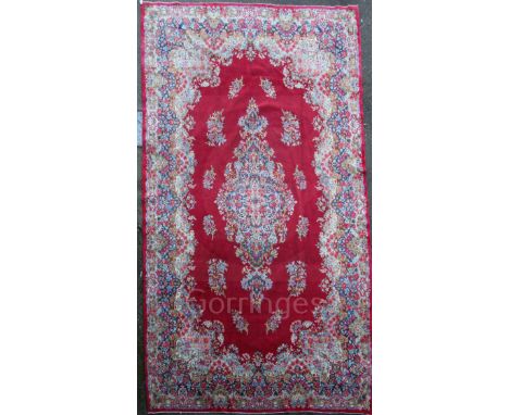 A North West Persian red ground carpet, with central foliate medallion surrounded with smaller floral motifs and extensive fl