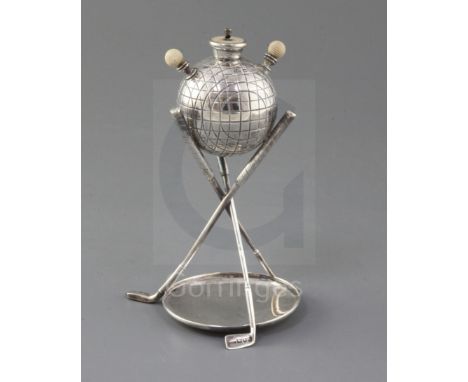 A late Victorian novelty silver and ivory mounted table club lighter, modelled as a golf ball above three crossed golf club s