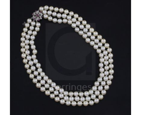 A three-strand uniform cultured pearl necklace with ruby, diamond and white gold (tests as 9ct) openwork flowerhead clasp, 40