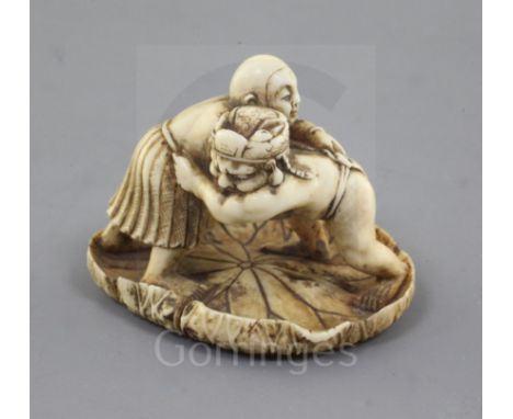 A Japanese ivory netsuke of two wrestlers, Meiji period, standing upon a curled lotus pad, unsigned, w. 4.2cm