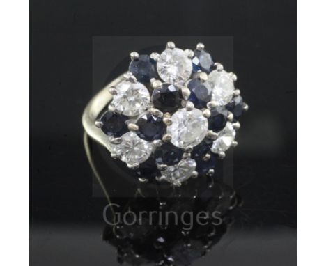 A diamond and sapphire cluster ring, set with seven brilliant cut diamonds and twelve sapphires, 18ct white gold shank, size 