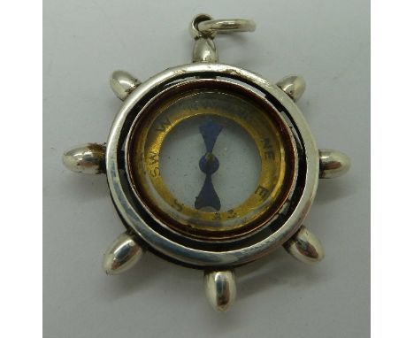 A white metal mounted compass fob in the form of a ship's wheel