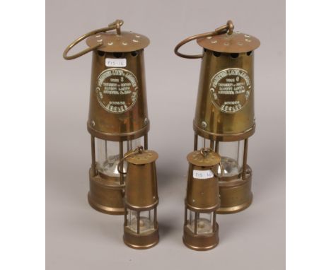 Two Eccles protector miners lamp type 6, along with two smaller brass miners lamps. 