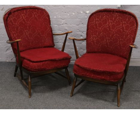 A pair of Ercol dark oak spindle back arm chairs with red floral upholstery. 