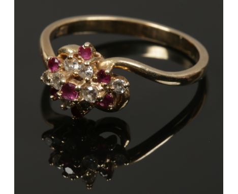 A 9ct gold ruby and diamond cluster ring with a crossover setting, size P. 