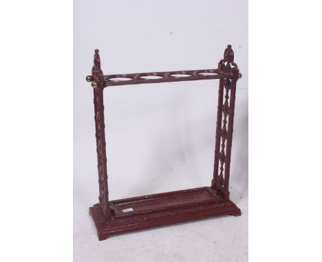 A Victorian style cast iron ochre red painted umbrella stick stand in the coalbrookedale style with trays to base Measures: 6