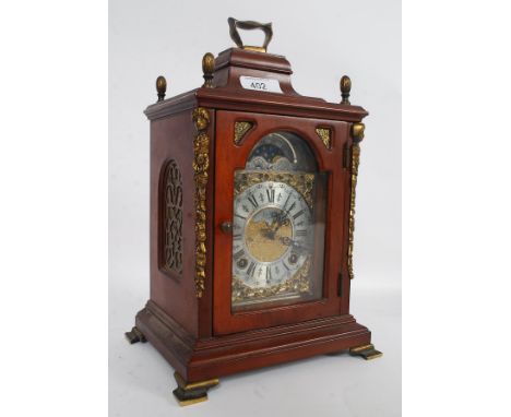 A Wuba Reproduction Mantel Clock, the arched top and brass carry handle encrusted with four foliate finials and the front cor