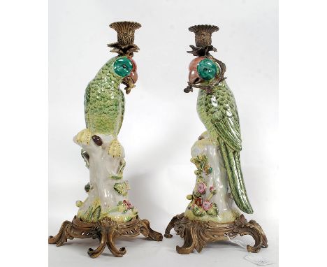 A pair of gilt metal and ceramic parrots in the form of candlesticks