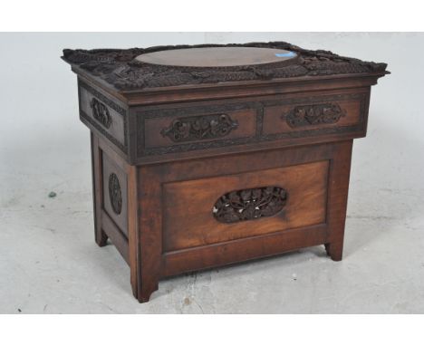 An early 20th century Chinese hardwood commode chest. The panelled body with pierced panels having profusely carved top with 