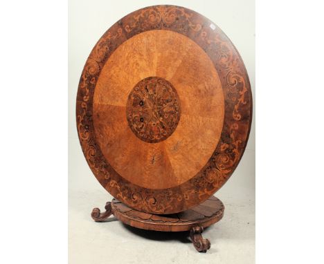 A large circular 19th century Victorian walnut and marquetry inlaid decorated tilt top pedestal dining table. Raised on a tri