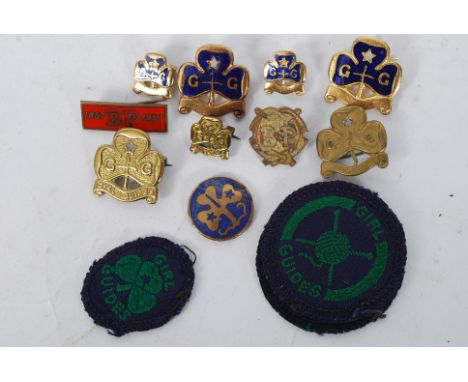 A collection of girl guide enamel badges dating to the 20th century along with patches ( see illustration )