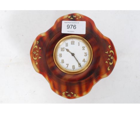 An early 20th century table clock being set within a tortoiseshell case of shaped form, the clock being 8 day swiss movement