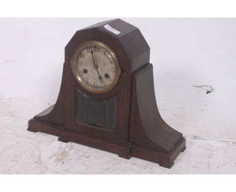 A 1930's Art Deco oak case mantel clock with glass viewing panel to front having brass 8 day movement set within unusual case