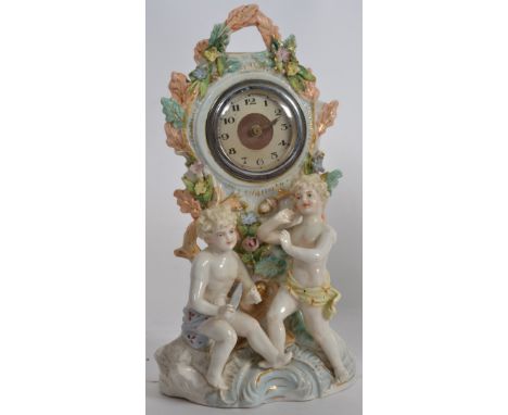 A Staffordshire bisque style mantel clock having central inset movement with cherub surrounds