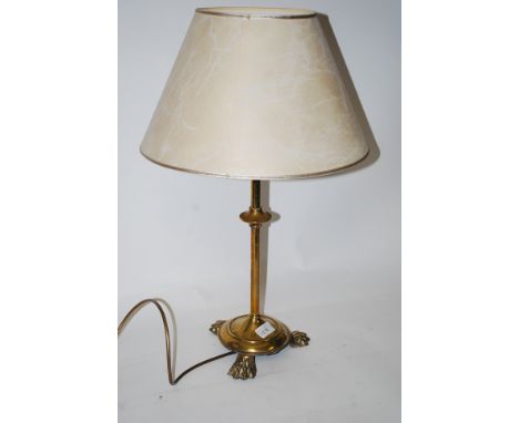 A 19th century brass tripod table lamp raised on Irish hairy paw feet with turned column having shade atop complete with wire