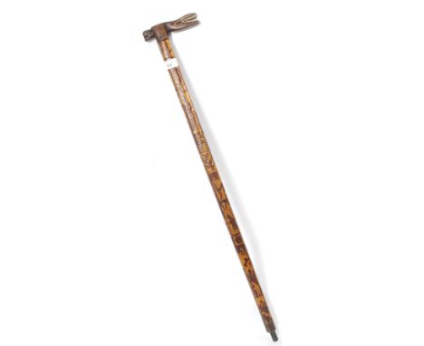 A good tribal walking stick with carved inlaid twin wood detailing having bone teeth alligator handle