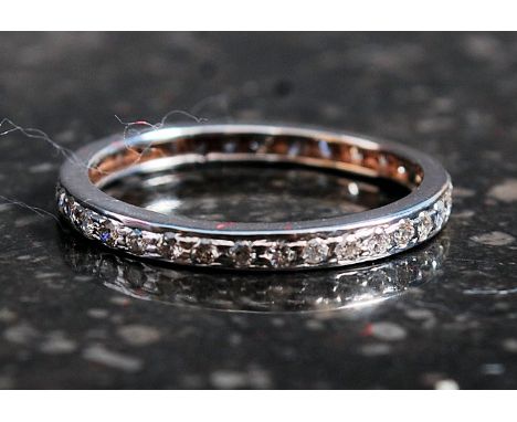 A ladies 18ct white gold full eternity diamond ring being stamped to inner hoop