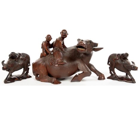 A CHINESE ROOTWOOD CARVING OF TWO FIGURES ON THE BACK OF A SEATED BUFFALO AND A PAIR OF SIMILAR SMALLER MODELS, FIRST 18CM H,
