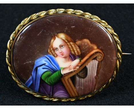A Continental porcelain oval plaque, painted with a portrait miniature of a lady with a harp, 6cm wide, mounted as a brooch, 