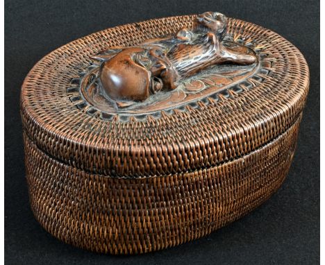 Tribal Art - an Inuit oval basket, the cover with hardwood panel carved with a demonic figure, 18.5cm wide 