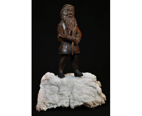A Black Forest figure, carved as a mountaineering gnome, he stands, atop a quartz boulder, 24.5cm high, early 20th century 