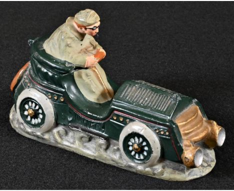 An early 20th century diecast novelty inkwell, cast as a gentleman driving a vintage motor car, hinged cover, 13cm long, earl