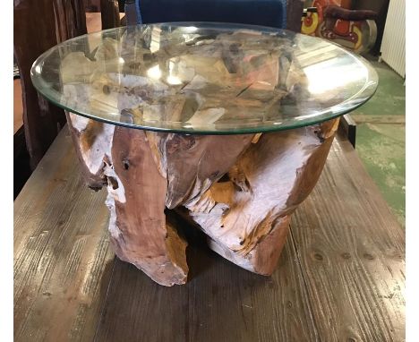 A Teak Tree Trunk Based coffee table with glass top.