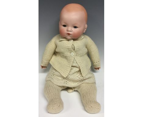 An Armand & Marseille bisque head baby doll, sleeping blue glass eyes, painted features, wearing a woollen cardigan, dress an