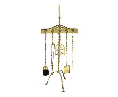 A set of five twisted brass fire tools on stand, 19th century, the stand surmounted by a single candle sconce and raised on a