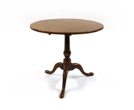 A George III yew occasional table,the circular tilt-top above a turned baluster column and a tripod base, terminating in pad 