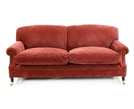 A George Smith Howard-style settee, the pad back and deep twin cushioned seat upholstered in red fabric, raised on turned har