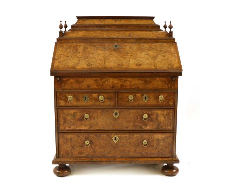 A walnut and feather banded bureau, 18th century and later, the stepped top with a hinged lid and four finials, above a fall 
