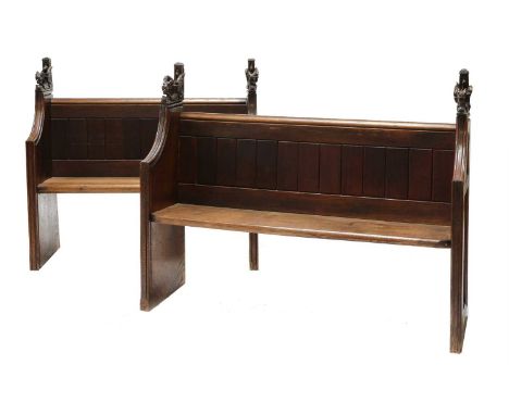 A near pair of oak church pews,19th century, each with a moulded rail and supports and each surmounted with composite dragon 
