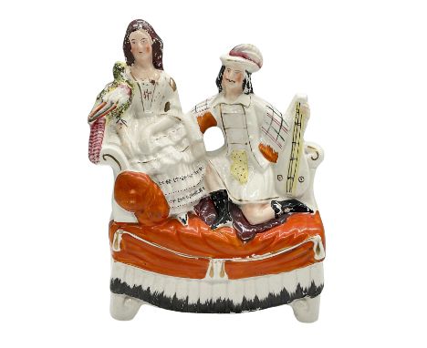 Handcrafted and hand-painted ceramic piece. Features a couple on a vibrant orange sofa, adorned with gilt accents. Dimensions