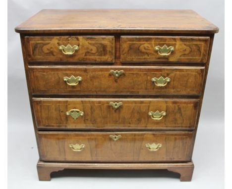 AN EARLY GEORGE III WALNUT VENEERED CHEST having crossbanded top over two in-line drawers and three graduating full width dra