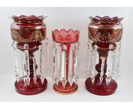 A PAIR OF LATE VICTORIAN RUBY GLASS LUSTRES, gilded decoration, on circular platform bases, suspending facet cut clear glass 