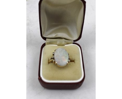 AN OPAL RING, the oval stone flanked by six small diamonds, 18ct gold mounted, size "k" 