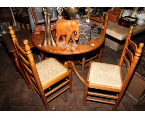Circular pine kitchen or dining table on single pillar base and four matching ladder back style chairs with rush seats 