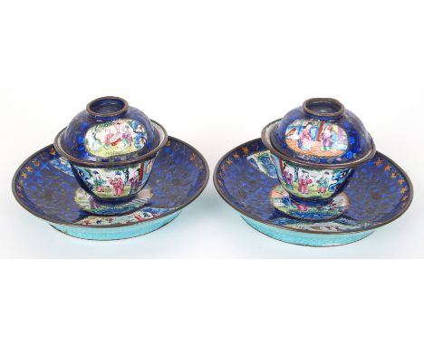 A pair of Canton enamel teabowls covers and saucers painted with figures on balconies on a blue and gilt ground (some damage)