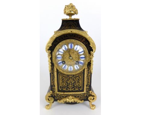 A Boulle style mantle clock with floral urn finial on a swept hood above convex enamel Roman numerals surrounded by scrolling