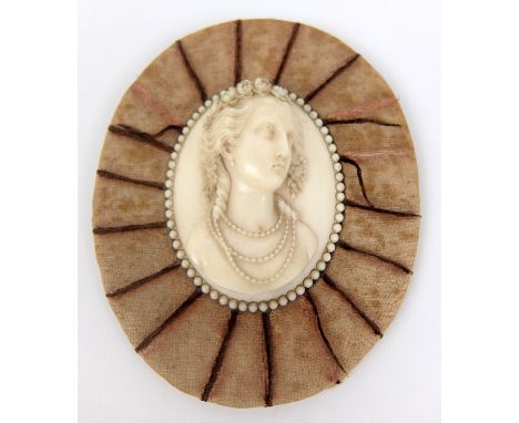 An early 19th Century carved ivory portrait plaque in high relief, of a young lady with flower garland in her hair, on oval v