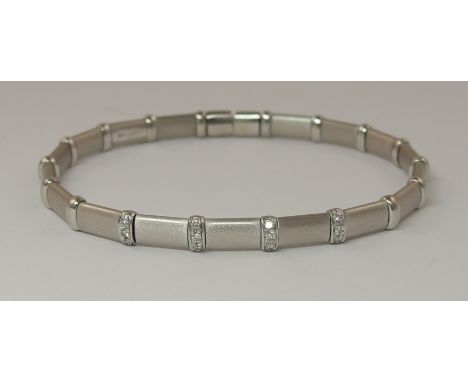 An Italian 18ct white gold sprung bangle matt textured links interspaced with shiny spacers the central four are set with bri