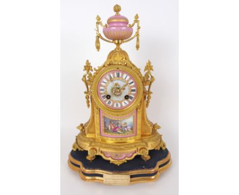 A Louis XVI style ormolu mantle clock by Hamilton Crichton & Co., Paris, with pink and gilt urn finial above a foliate dial a