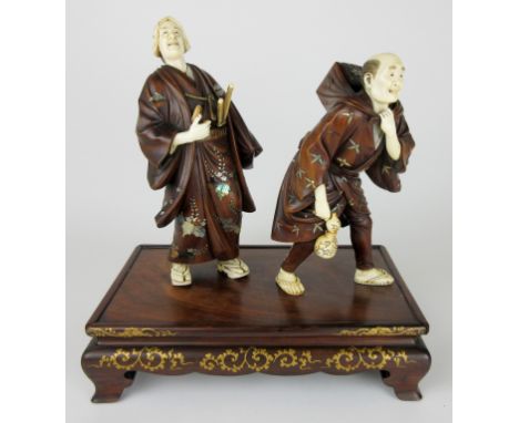 A Japanese Shibayama ivory and wood group of a Samurai and his attendant,  the smiling warrior leaning backwards, his hand to