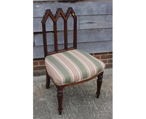 A carved oak gothic design side chair with triple arch back, seat upholstered in a striped fabric, on turned and octagonal su