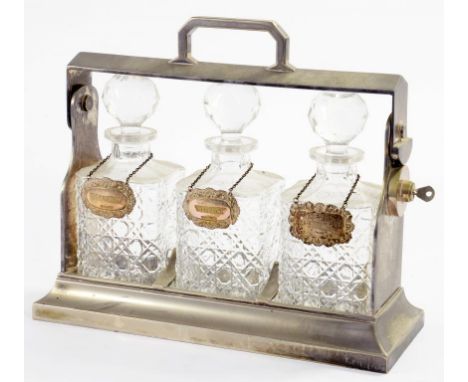 AN EPNS TANTALUS, EARLY 20TH C  with a set of three cut glass decanters and stoppers, 29cm h and a set of three silver decant