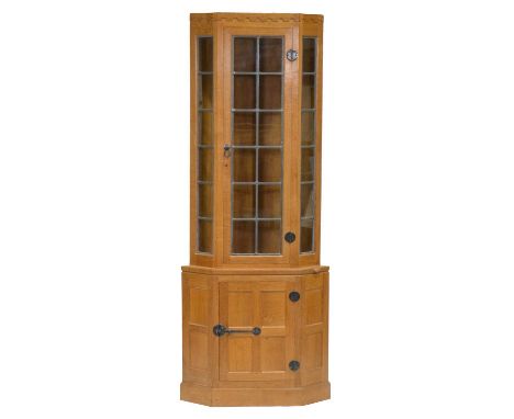 Robert 'Mouseman' Thompson of Kilburn, an oak floorstanding corner cabinet, lead-glazed upper section enclosing two glass she