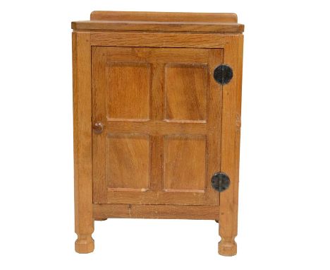 Robert 'Mouseman' Thompson of Kilburn, an oak panelled bedside cupboard, 1970's, with raised upstand, four-panel cupboard fit